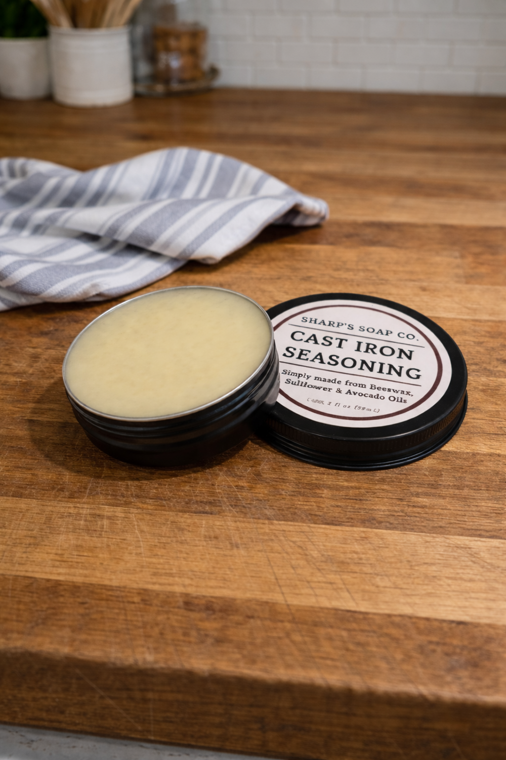 Bar of soap in a container on a wooden surface with a towel in the background