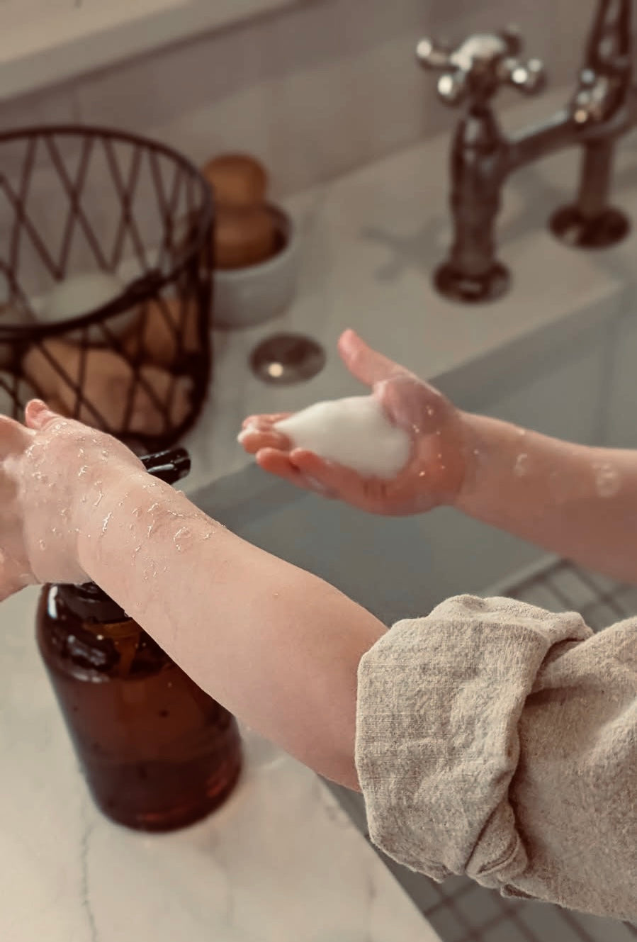 Two hands with soap bubbles in a bathroom setting