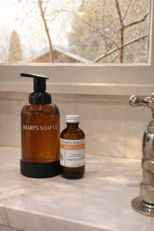 Two bottles of Sharp's Soap Co. on a bathroom counter with a window in the background.